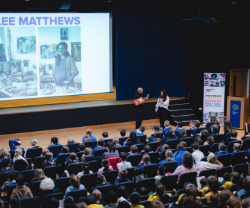 Children in an auditorium with Lee giving a presentation on her work